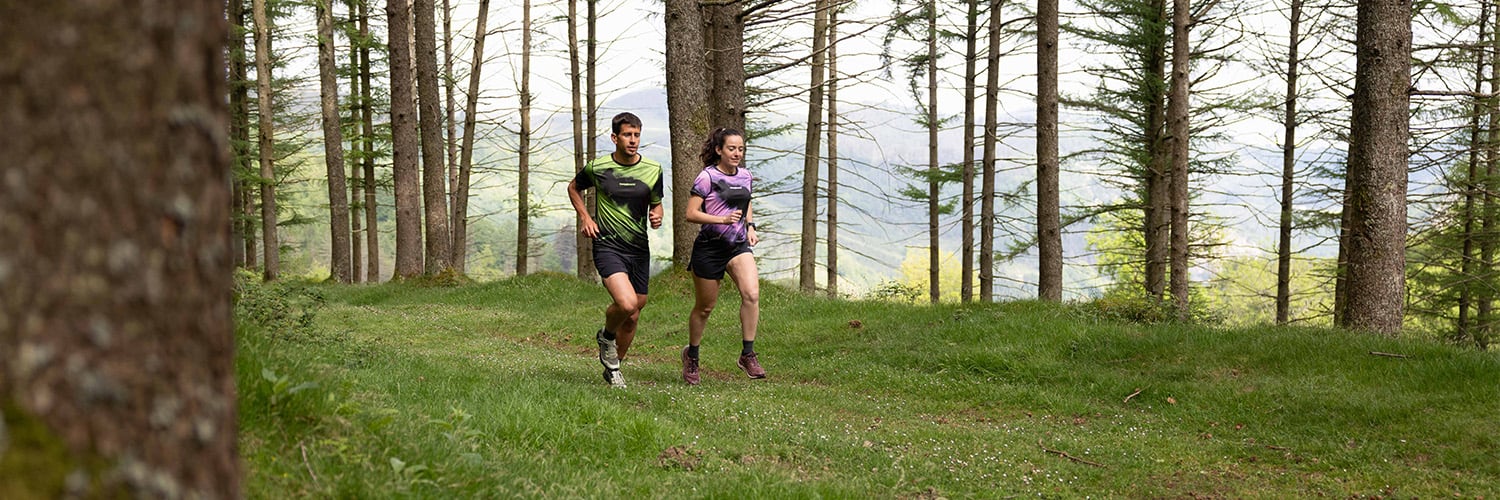 Corredores de trail running con equipación Trangoworld en un sendero por el bosque