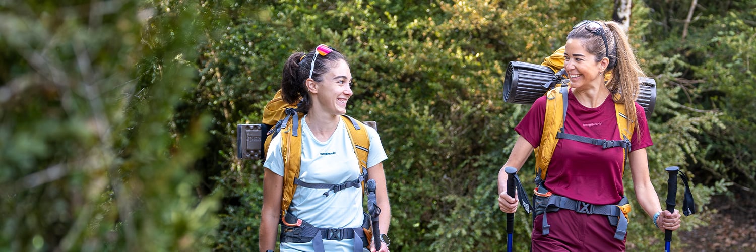 Montañeras con mochila de travesía caminando por sendero