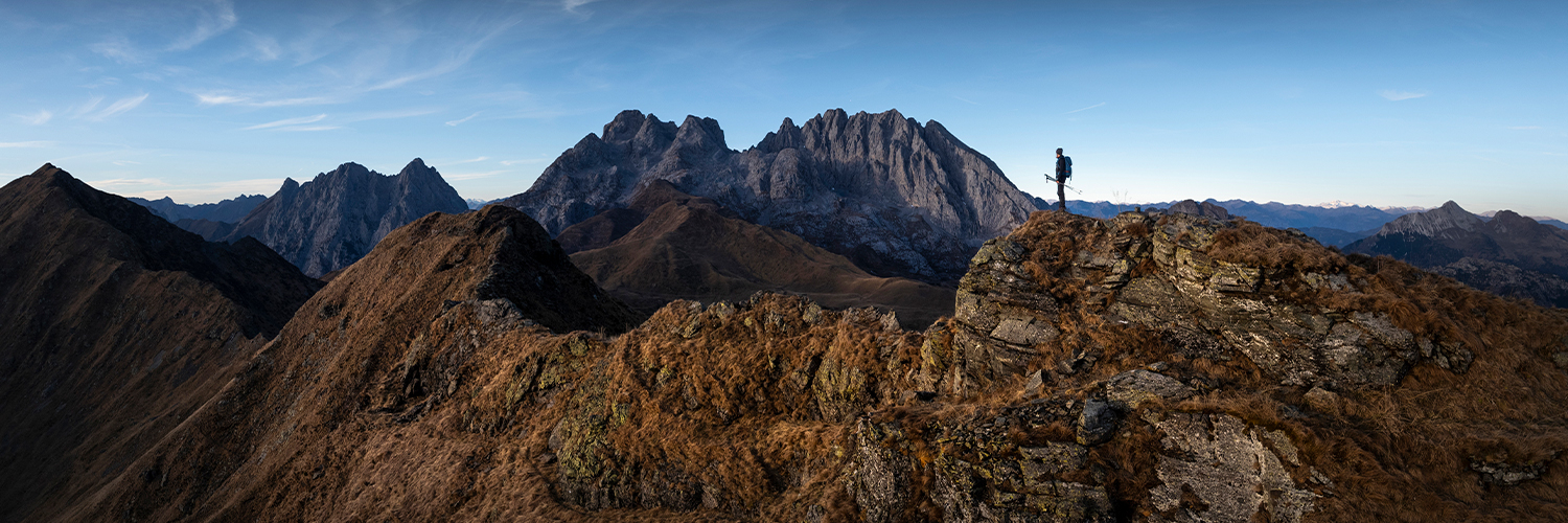 Senderista en una cresta rodeado de un paisaje de montaña