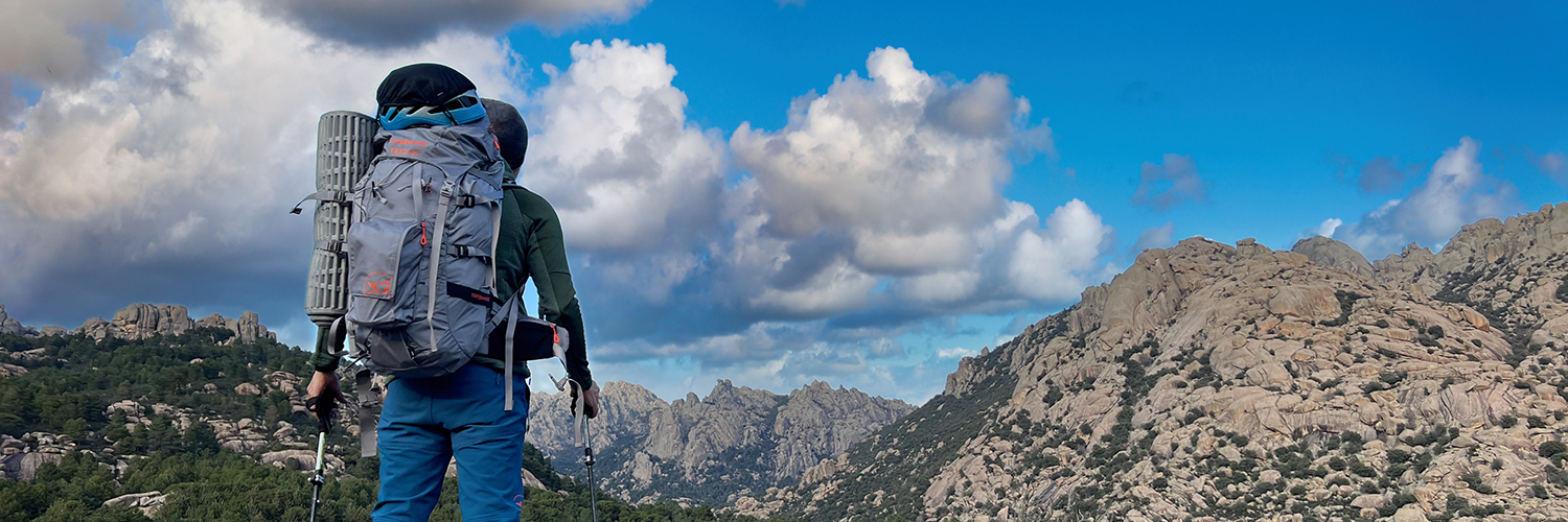 Persona equipada con mochila de trekking Trangoworld y fondo montañoso