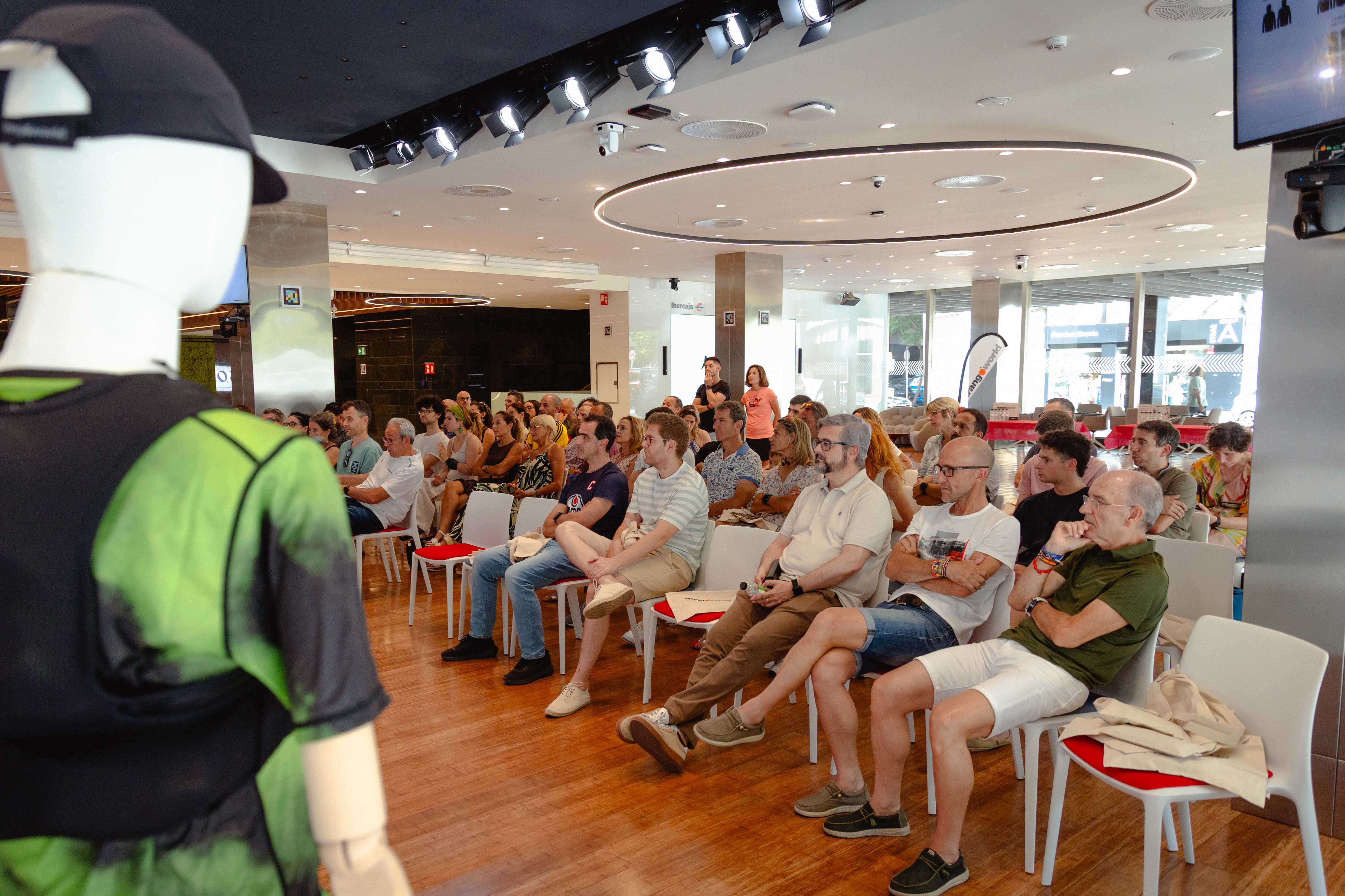 P&uacute;blico sentado en una sala escuchando una charla, con maniqu&iacute; en primer plano