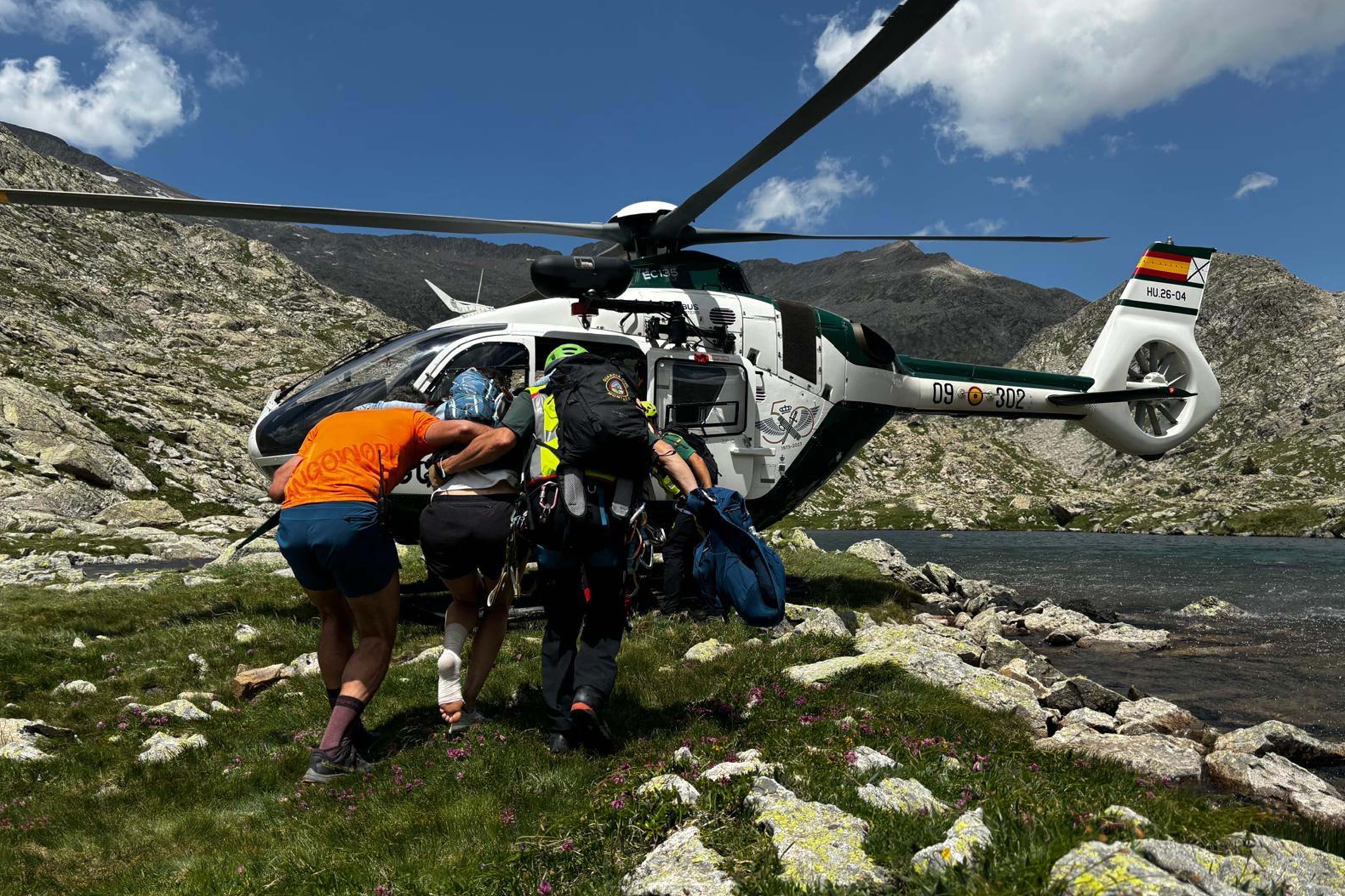 Rescate en helicóptero durante una prueba de trail running Helicóptero de rescate evacuando a un corredor herido junto a un lago de montaña