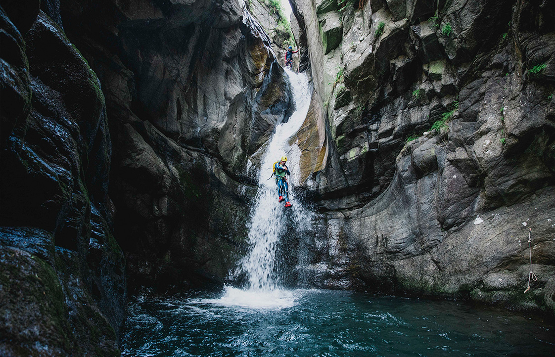 Barranquista deslizándose por un tobogán en el Barranco de Núria Barranquista descendiendo una cascada encajonada en el barranco de Núria, Pirineo catalán