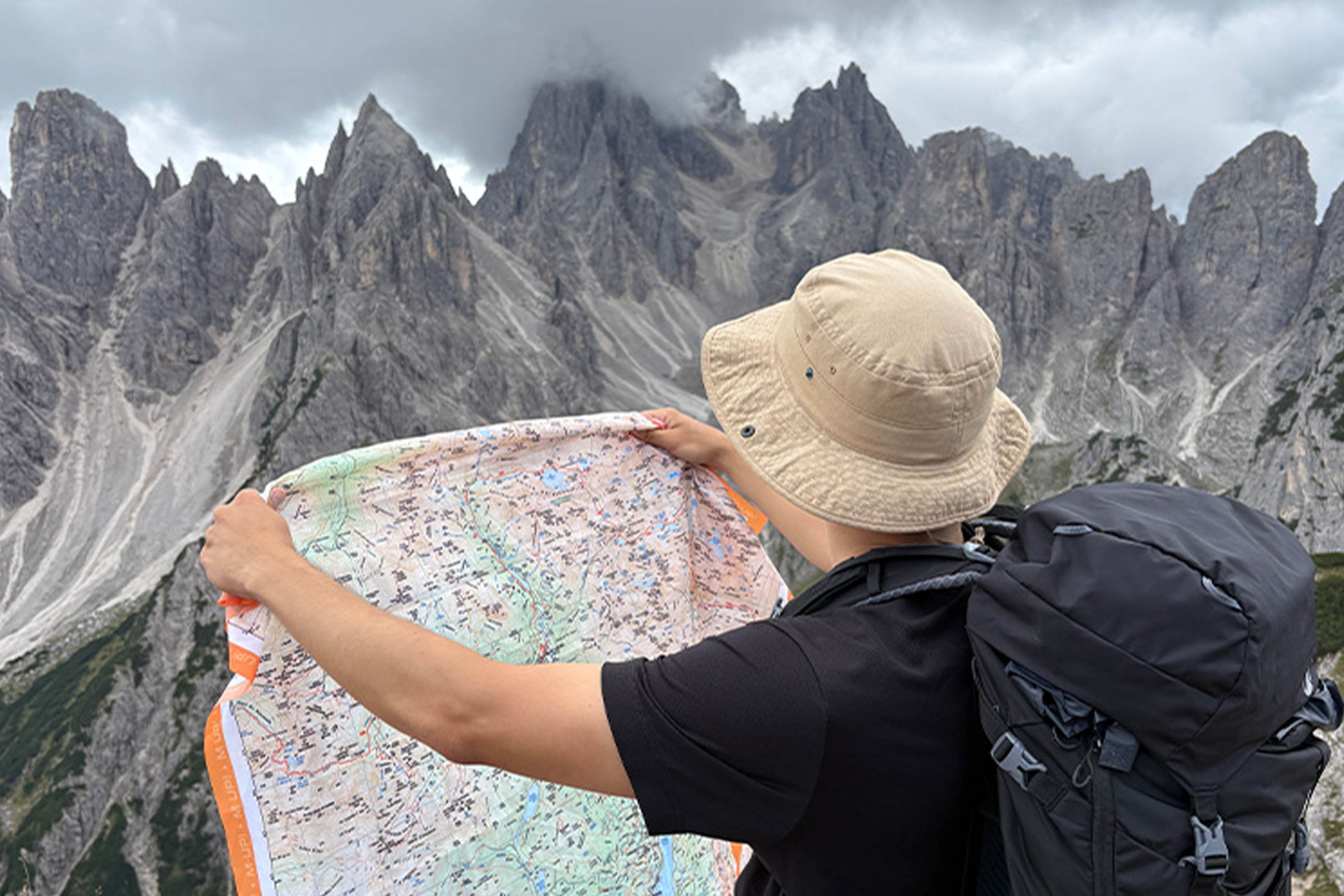 Planificación de ruta de trekking en montaña · Trangoworld Senderista consultando mapa de montaña con paredes rocosas de fondo