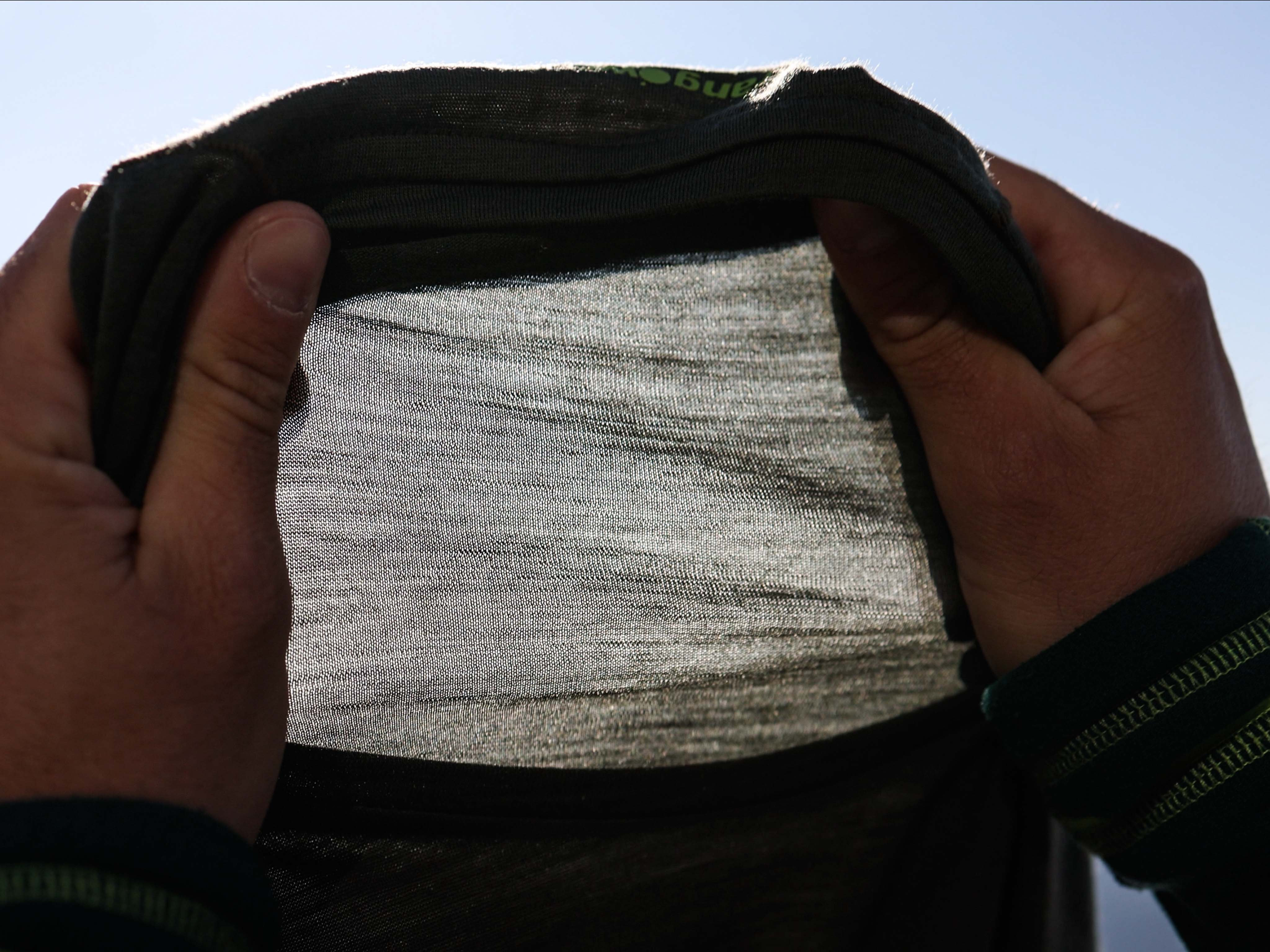 Primer plano de manos mostrando la textura de un tejido de lana merino Detalle a contraluz del tejido de lana merino Trangoworld mostrando su finura y ligereza