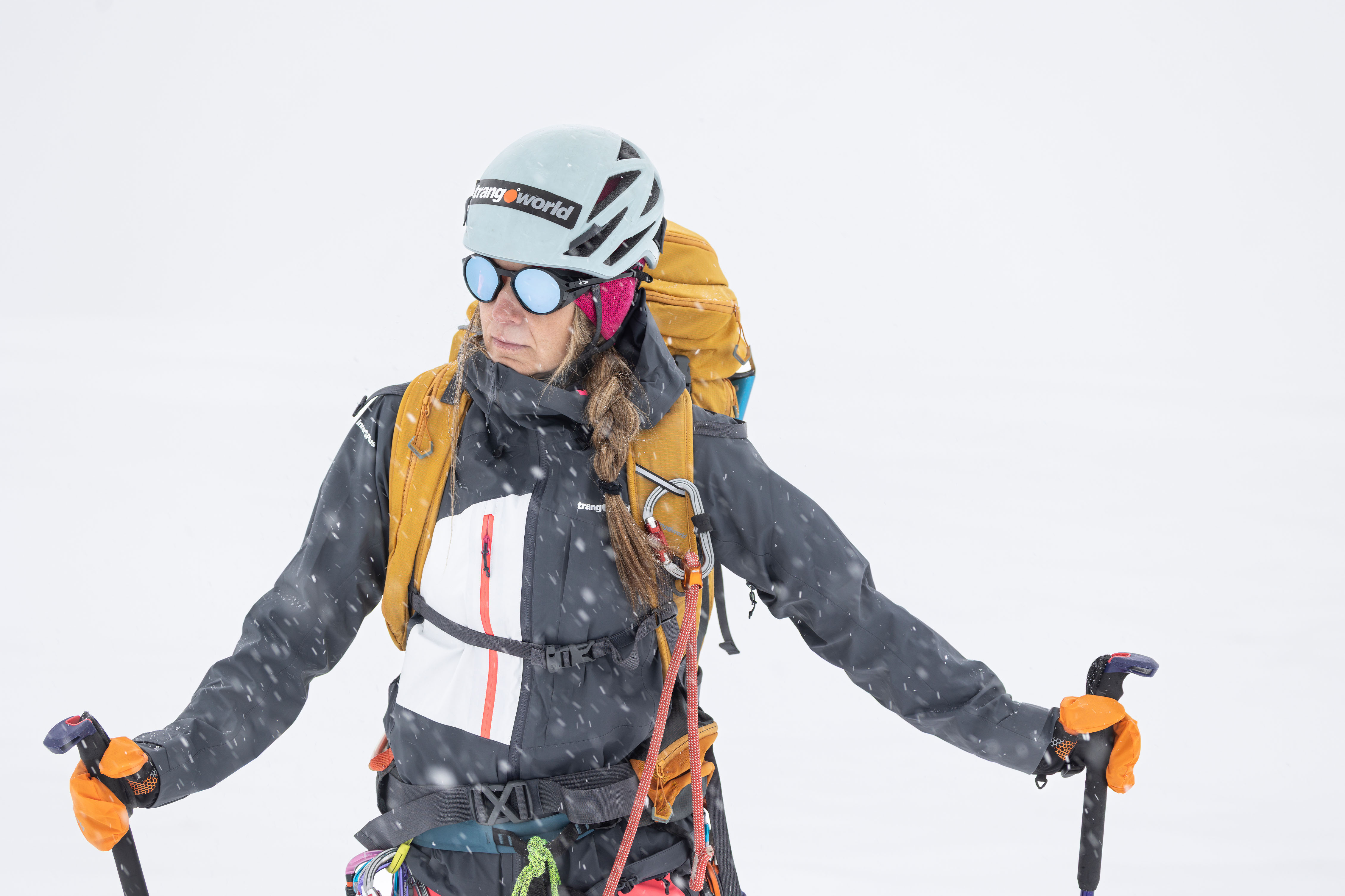 Chaqueta impermeable para montaña en invierno. Tercera capa. Trangoworld Mujer con chaqueta impermeable Trangoworld como tercera capa en nevada intensa con mochila y bastones